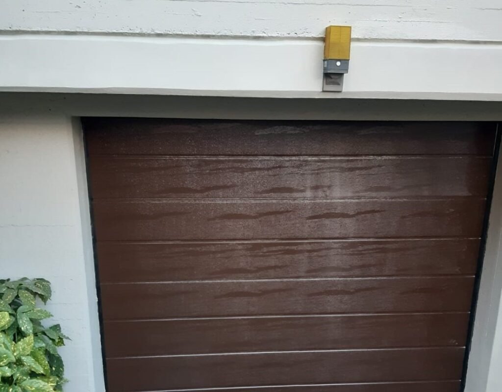 Porta garage sezionale marrone motorizzata, con lampeggiante sopra il vano