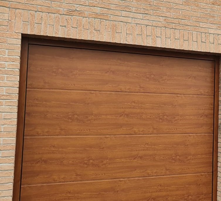 Porta garage sezionale effetto rovere dorato installata su una casa
